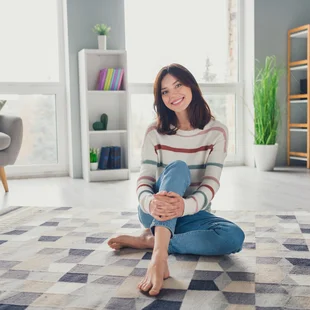 Illustration - Ihr Experte für schönes Wohnen - Eine junge Frau sitzt im Wohnzimmer auf einem Teppich.
