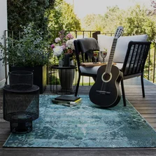 Illustration - Ihr Experte für schönes Wohnen - Ein blau gemusterter Orient Vintage Outdoor Teppich liegt auf einem Balkon