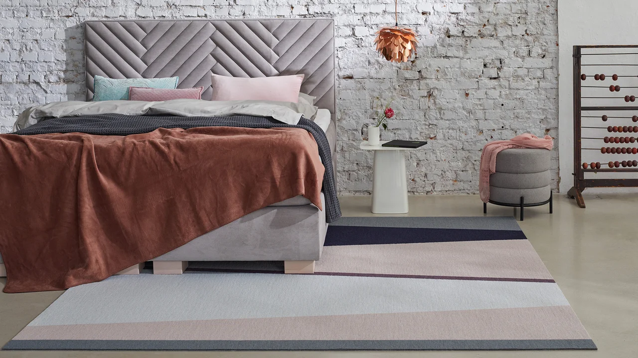 Ein Teppich liegt im Schlafzimmer halb unter dem Bett. - Ein Teppich liegt im Schlafzimmer halb unter dem Bett.